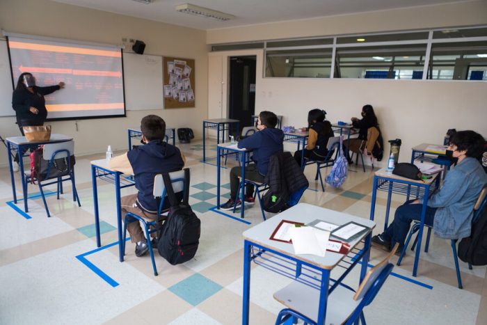 Estudiantes de educaicón básica sentados en sus pupitre, mirando a la pizarra