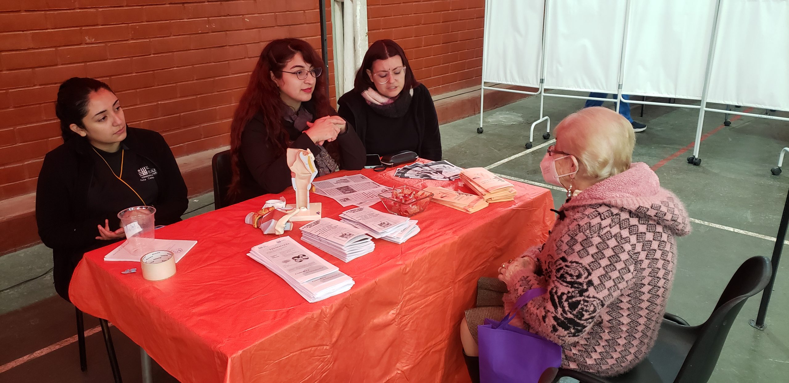 Estudiantes UCSH atienden en una mesa a adulta mayor.