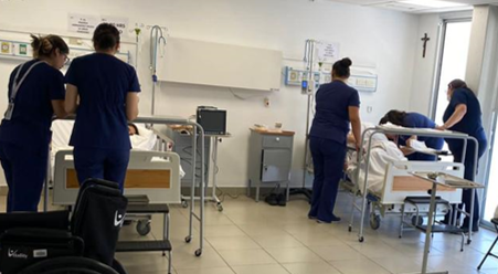 Estudiantes atendiendo pacientes en hospital simulado.